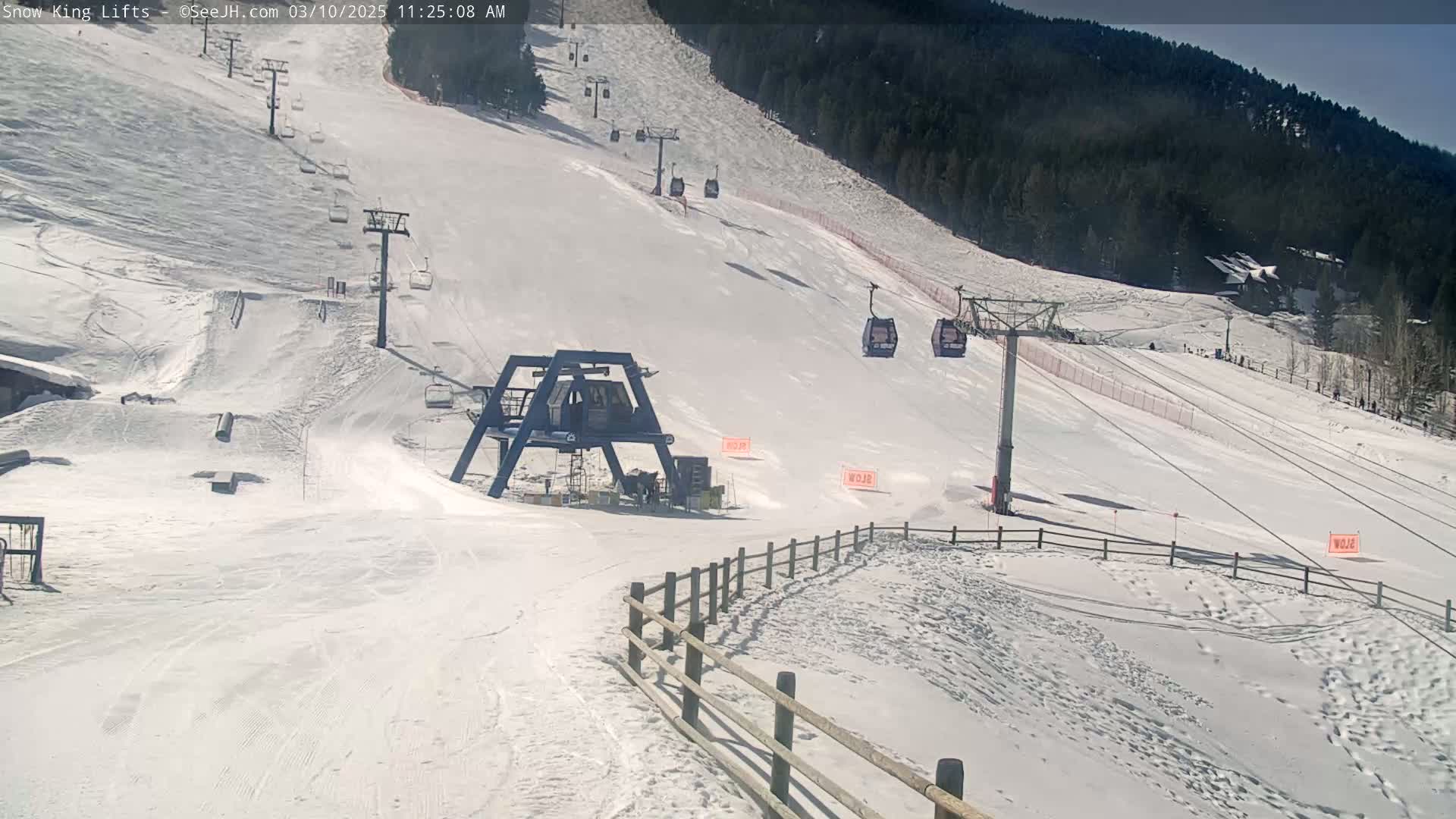 A snow-covered ski slope with several chairlifts and a mountain in the background on a sunny day.