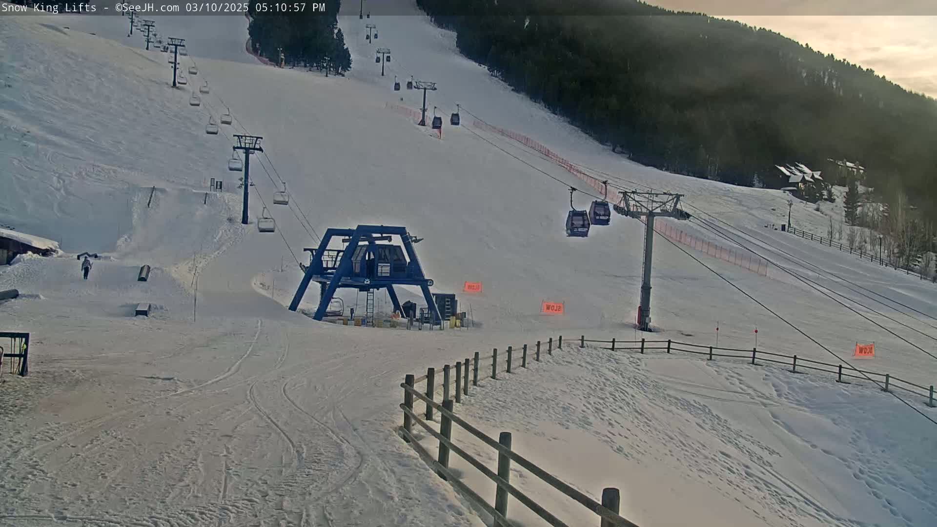 A snow-covered ski slope with several chairlifts and a ski lift base station under partly cloudy skies.