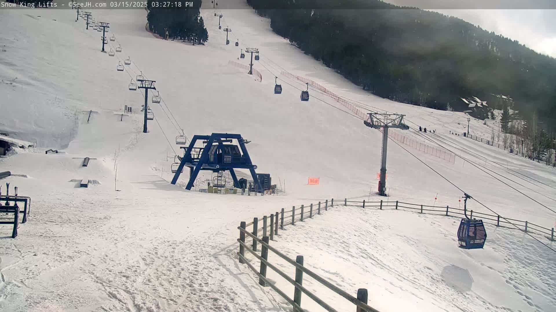 A snow-covered ski slope with several chairlifts and a gondola, under an overcast sky.