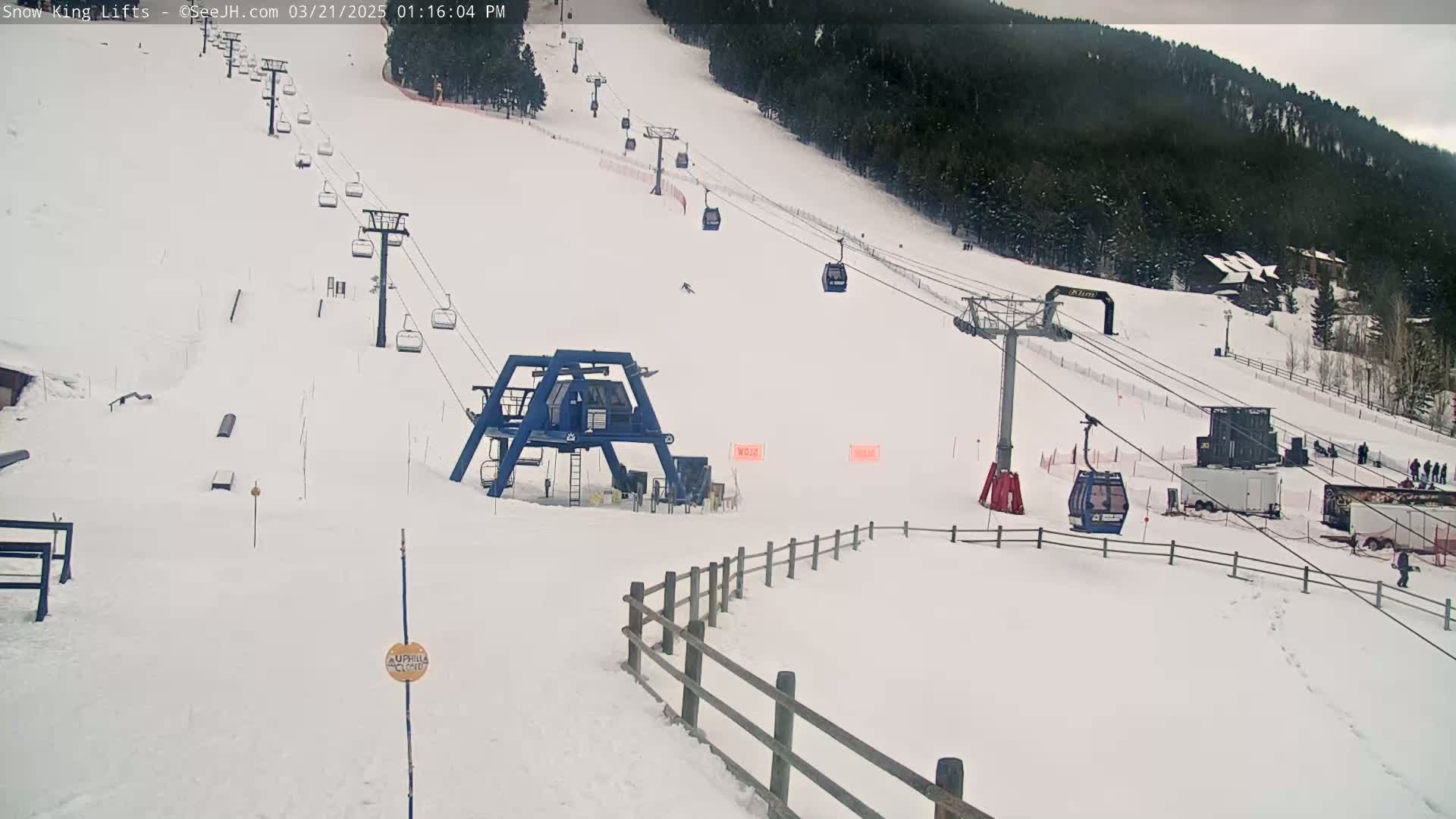 A snow-covered ski slope with several chairlifts and a base area, under an overcast sky.