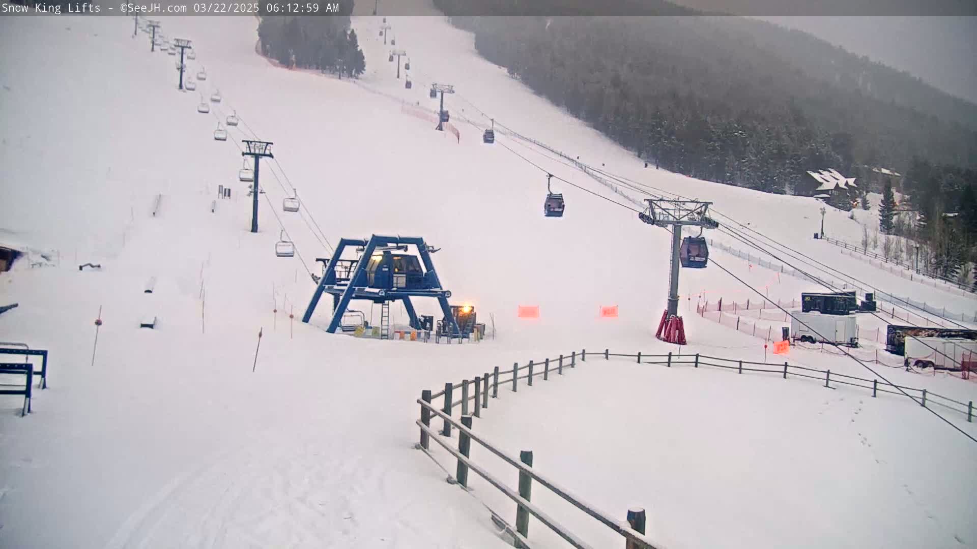 A snow-covered ski slope with several chairlifts and a base area, under an overcast sky.