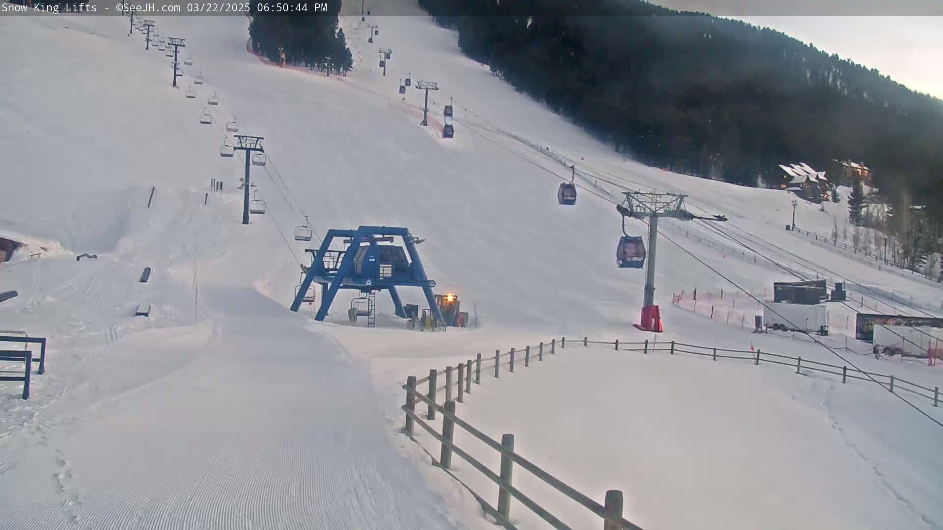 A snow-covered ski slope with several chairlifts and a ski lift base station, under overcast skies.
