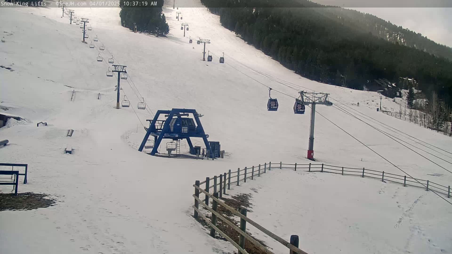 A snow-covered ski slope with several chairlifts and a ski lift base station, under an overcast sky.