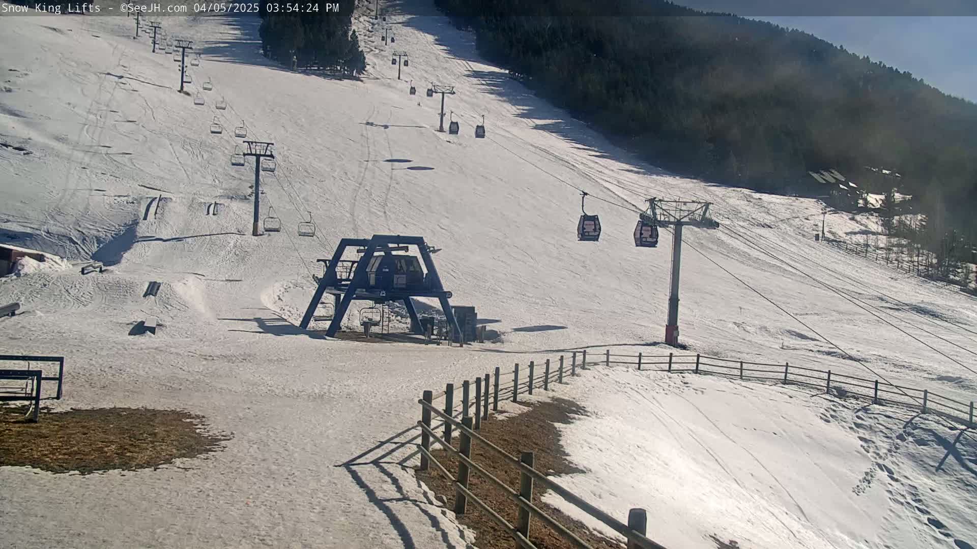 A snow-covered ski slope with several chairlifts and a gondola, under sunny conditions.