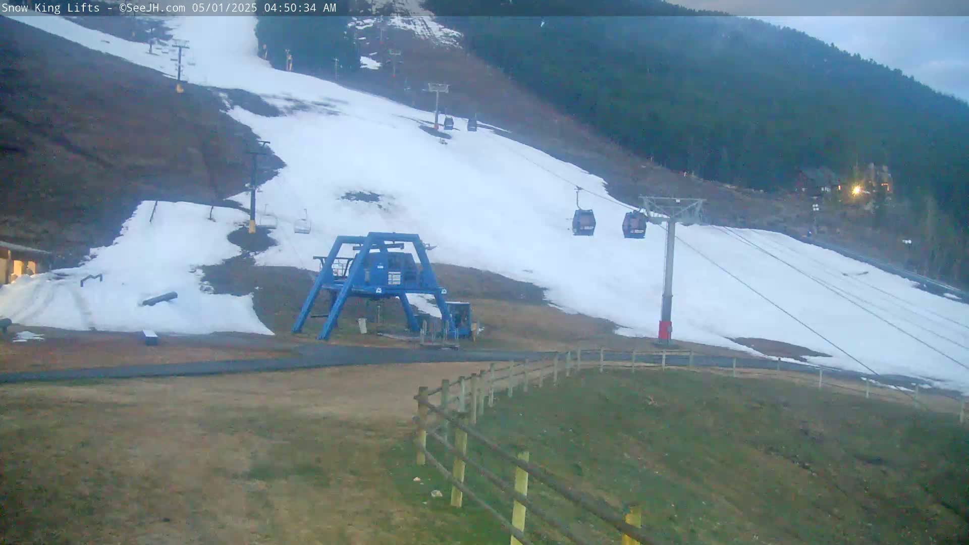 A snow-covered ski slope with chairlifts and a ski lift base station is visible under overcast conditions.