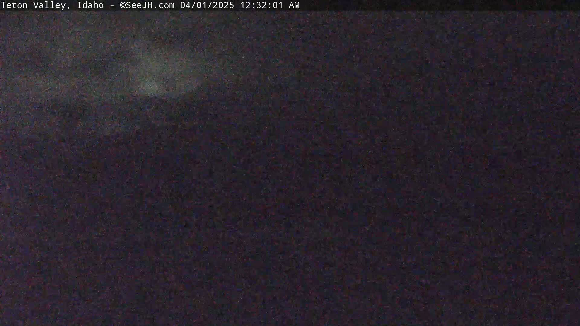 A dark, blurry nighttime image shows a mostly featureless landscape under a dark sky.
