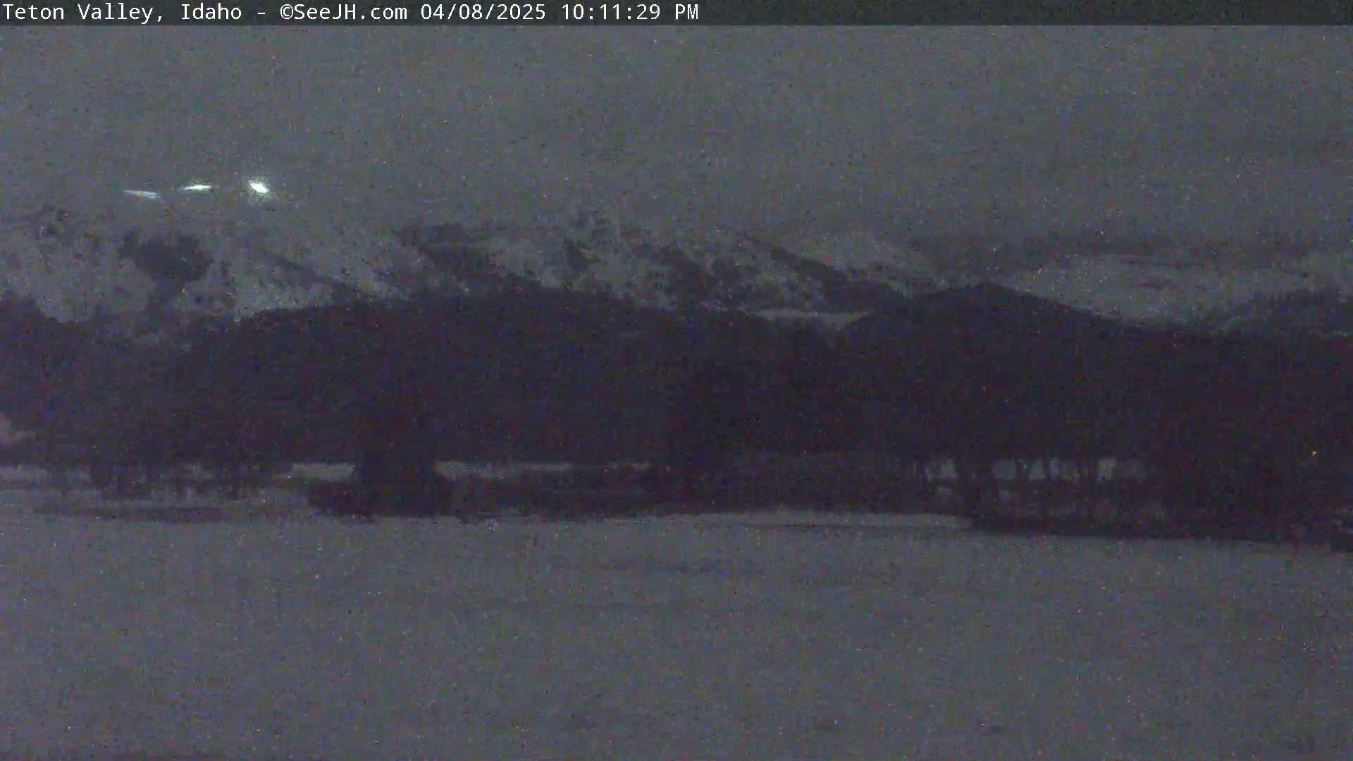 A dark, snowy mountain range is visible under a twilight sky.