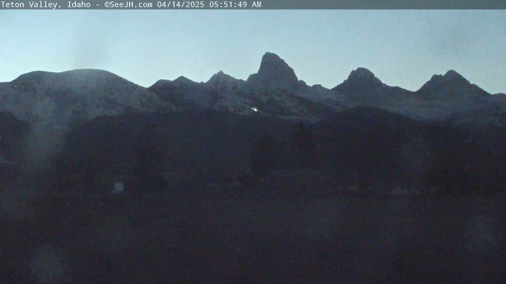 A dark, mountainous landscape is visible at dawn under a clear, dusky sky.
