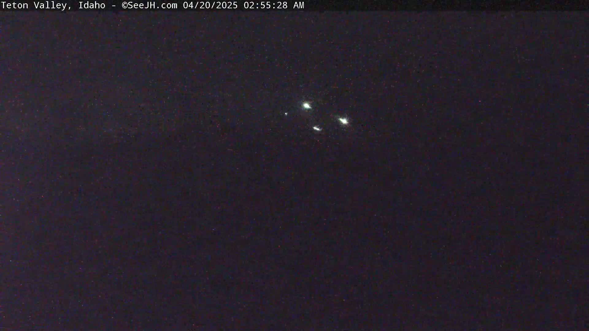 A dark night sky shows a cluster of bright lights.