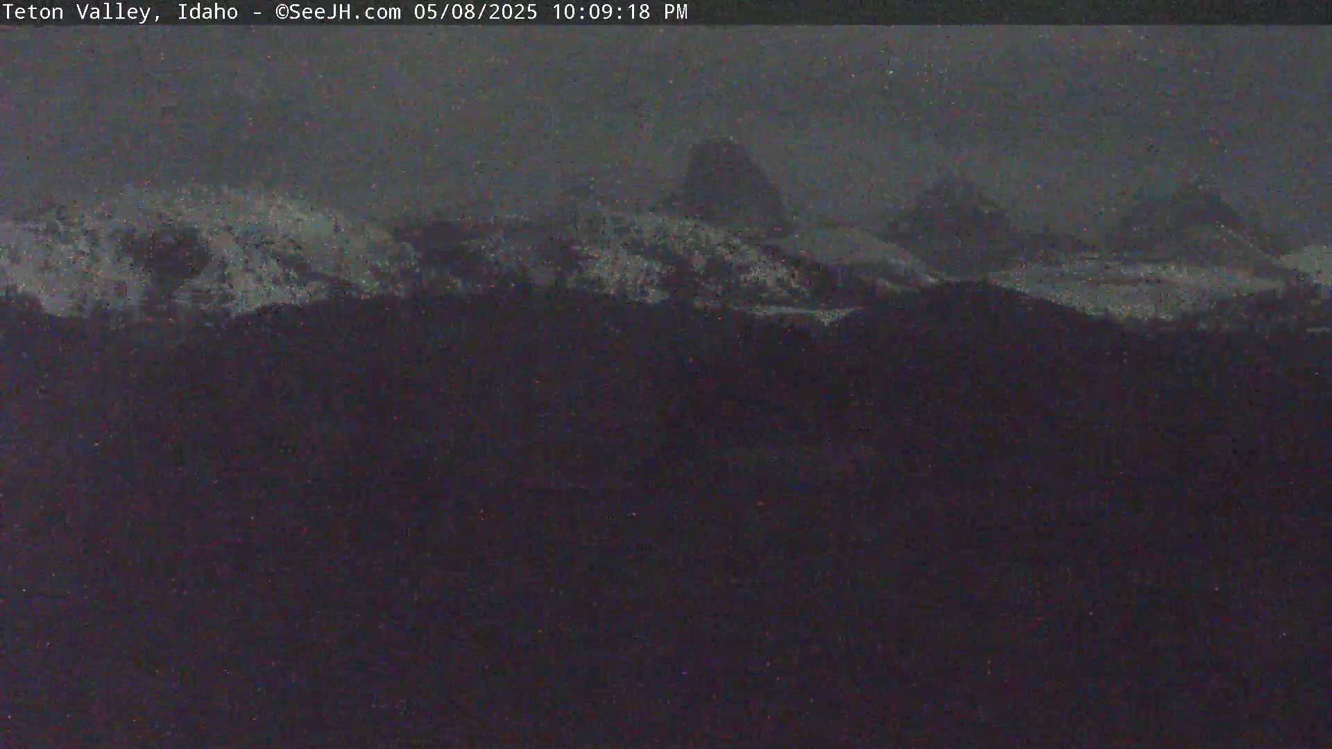 Snow-covered mountains are visible under a dark, overcast sky.
