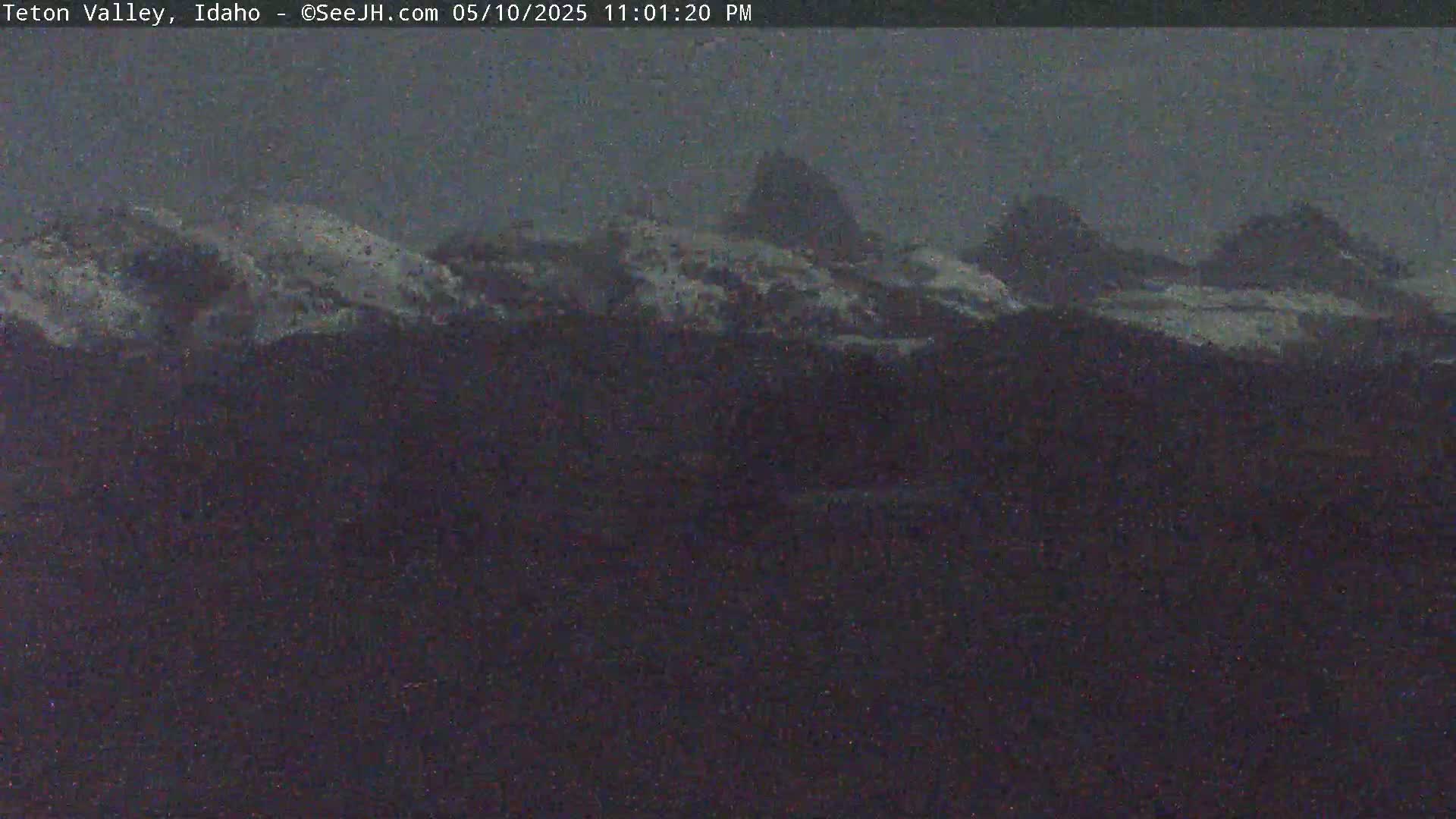Snow-dusted mountain peaks are visible under a dark, overcast sky.