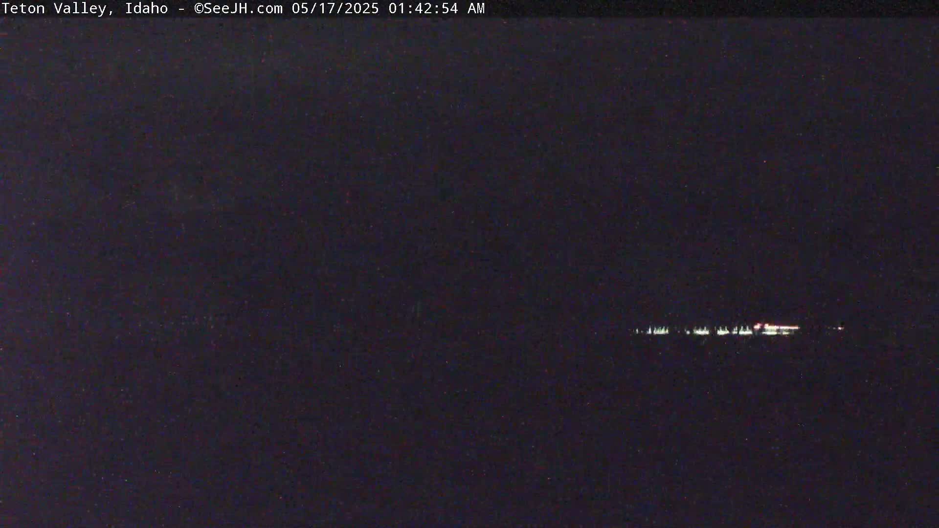 A nighttime, low-light view shows a distant line of lights on the horizon.