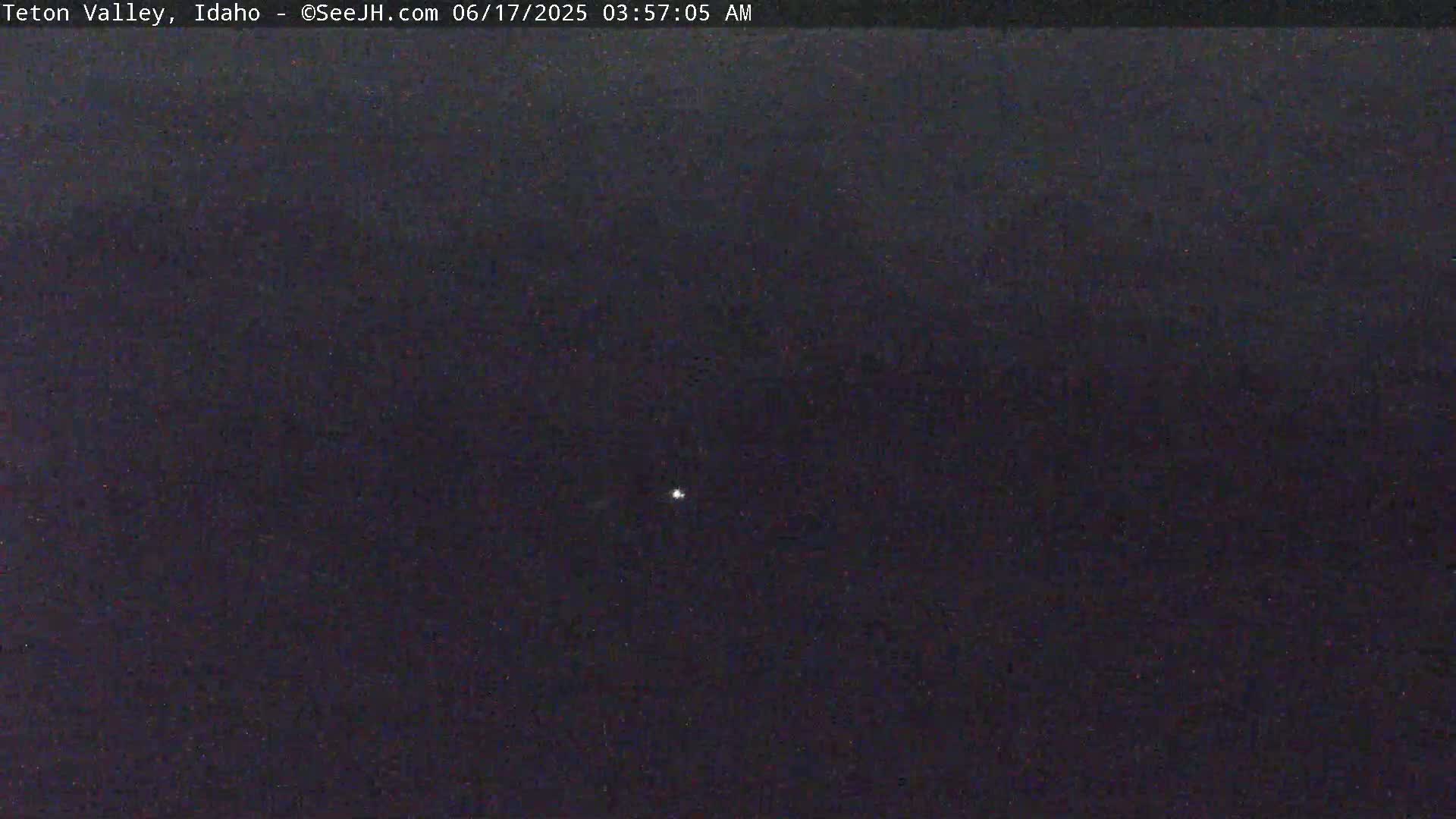 A dark, nighttime scene shows a single, faint light in the distance.