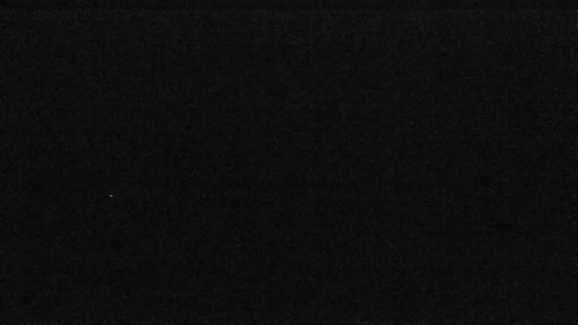 The image displays a very dark, grainy field with a single, tiny, faint white speck near the bottom center.