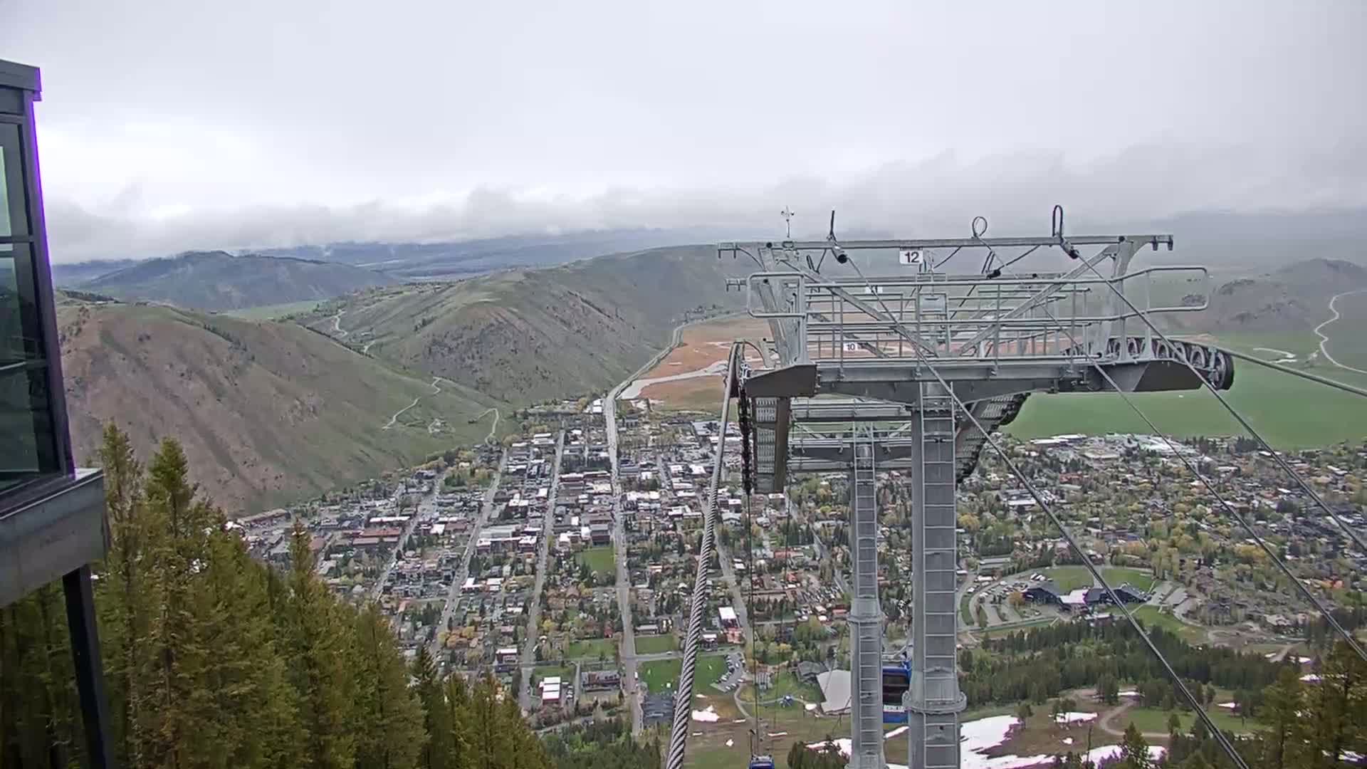 A chairlift overlooks a town nestled in a valley, under an overcast sky.