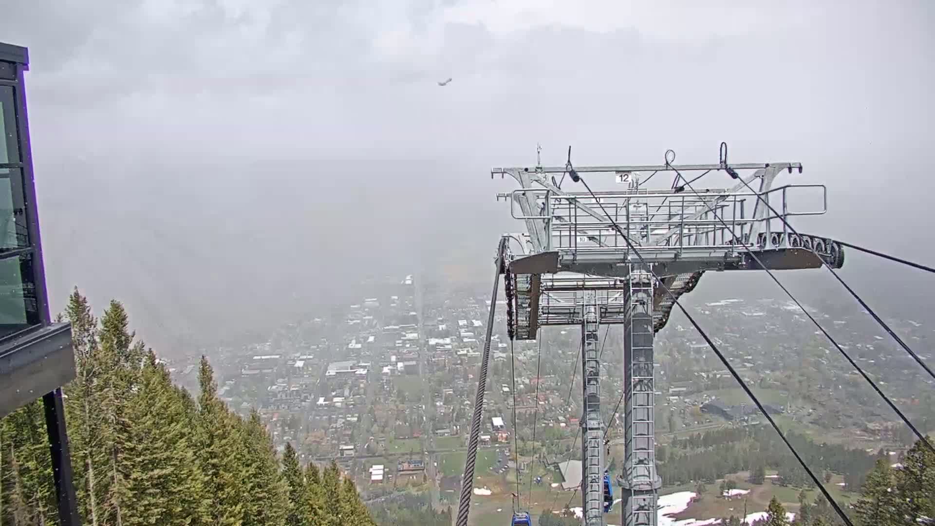 A hazy view of a town stretches out below a chairlift on a cloudy day.