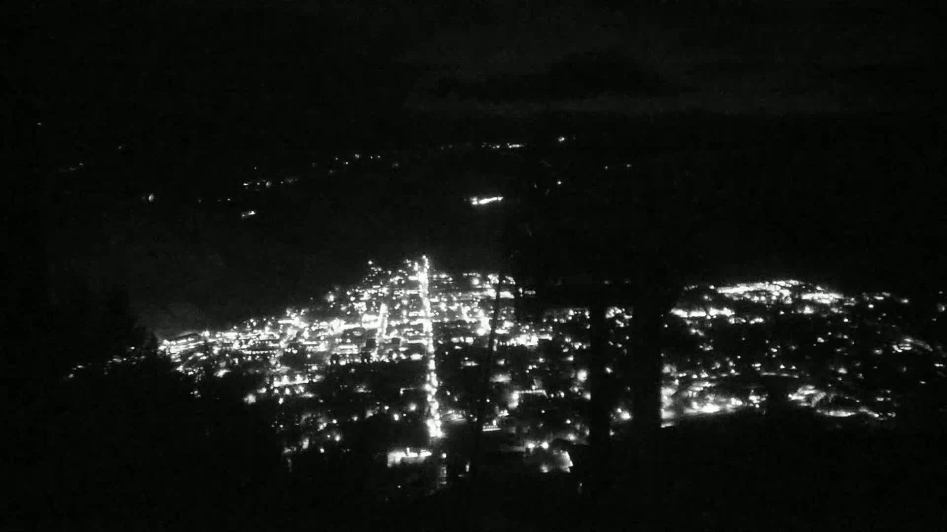 A nighttime, high-angle view shows a city illuminated by many small lights.