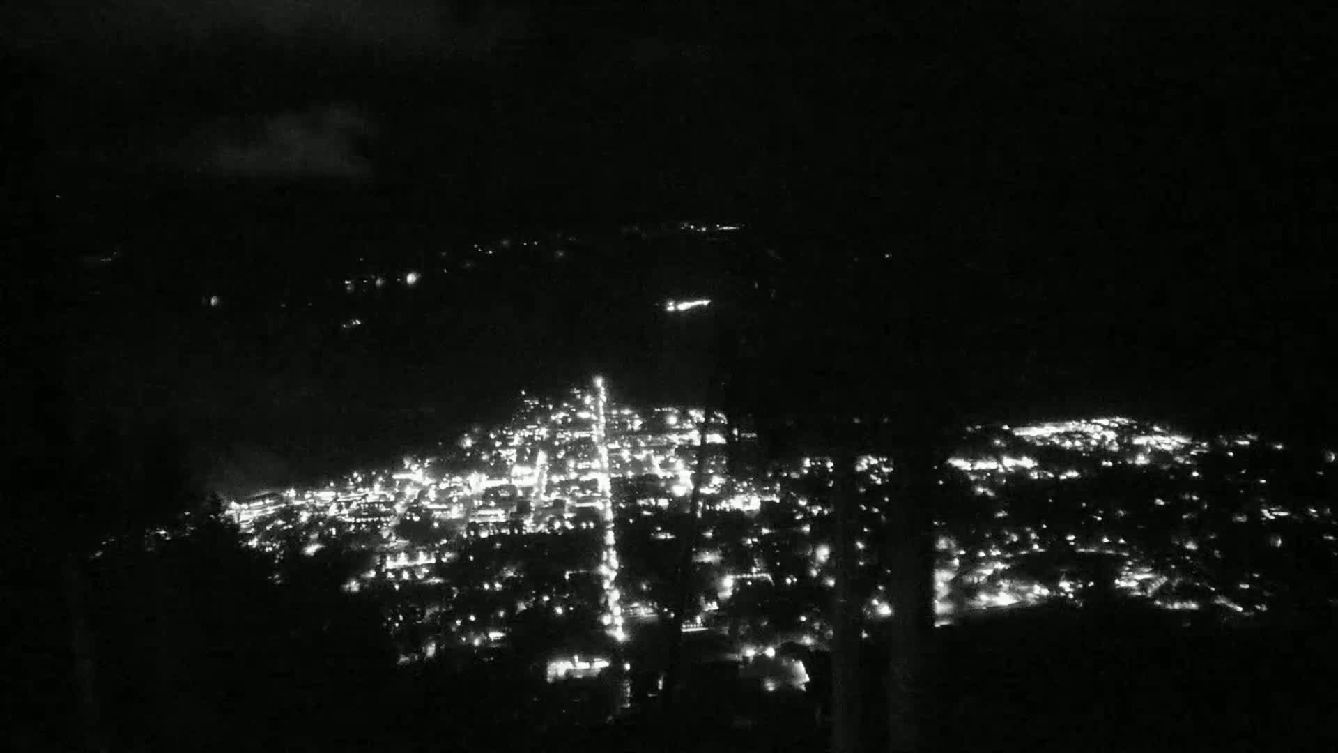 A nighttime, aerial view shows a city illuminated by many small lights.