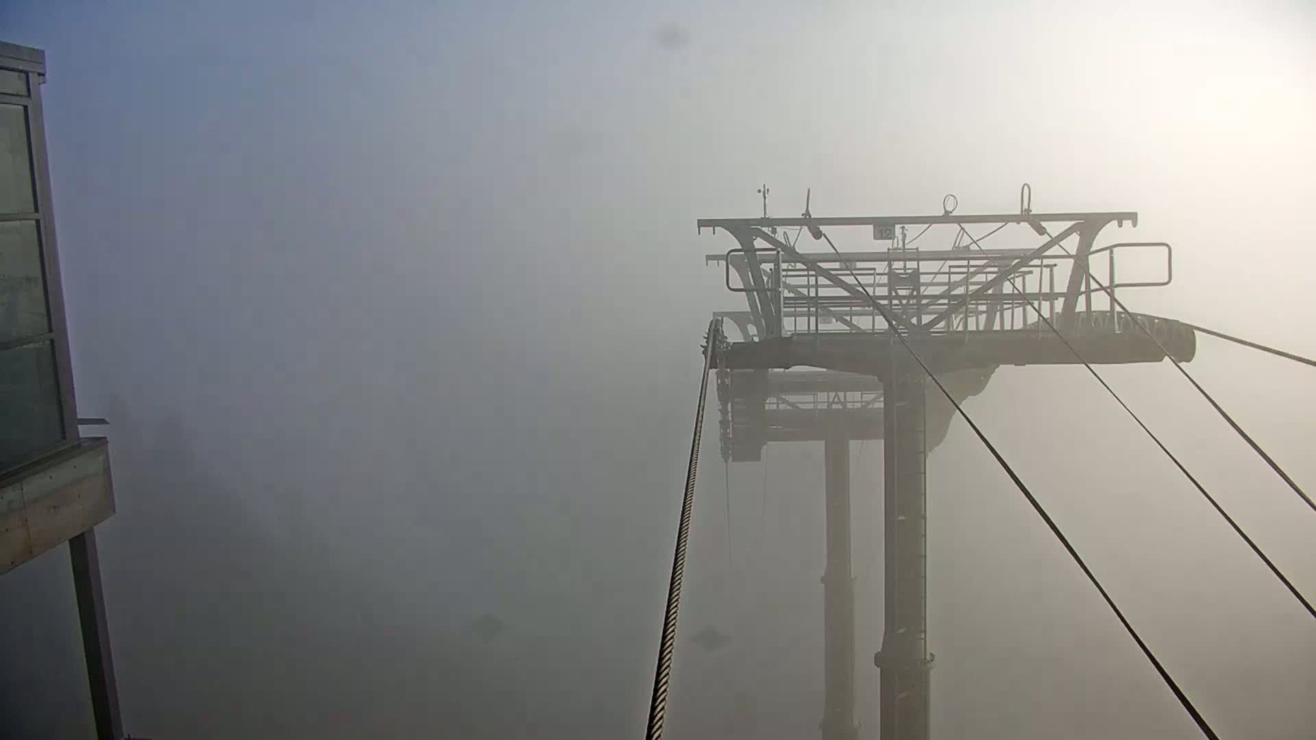 A chairlift cable and structure are shrouded in thick fog.