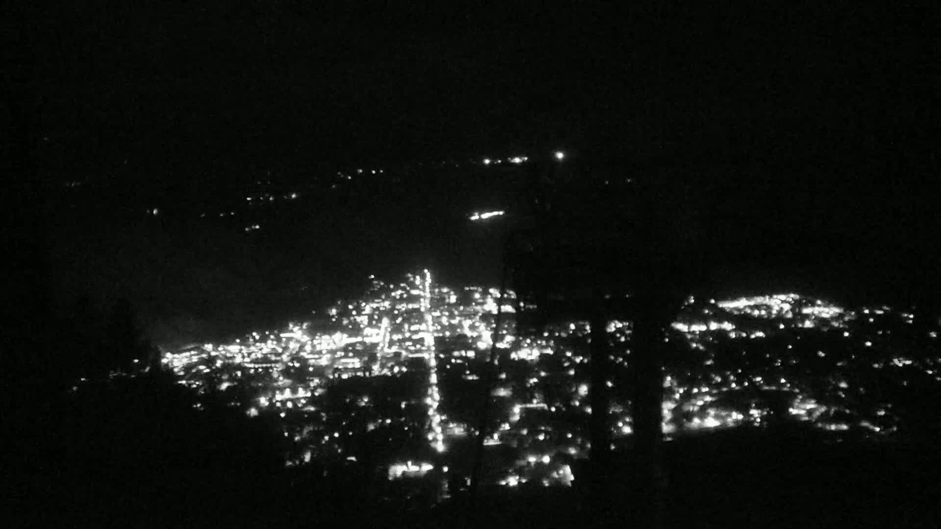A nighttime view of a city's illuminated streets and buildings from a distant vantage point.