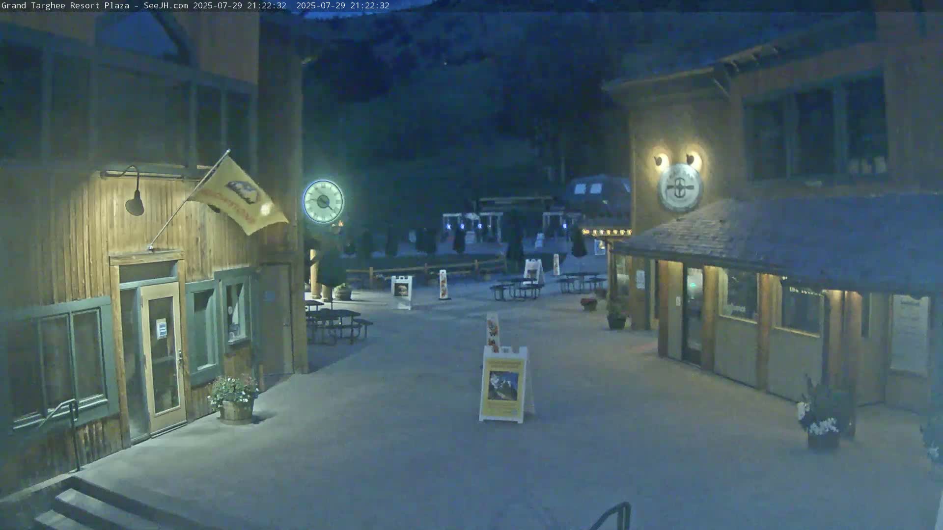 A plaza with two wooden buildings at night, under dark conditions.