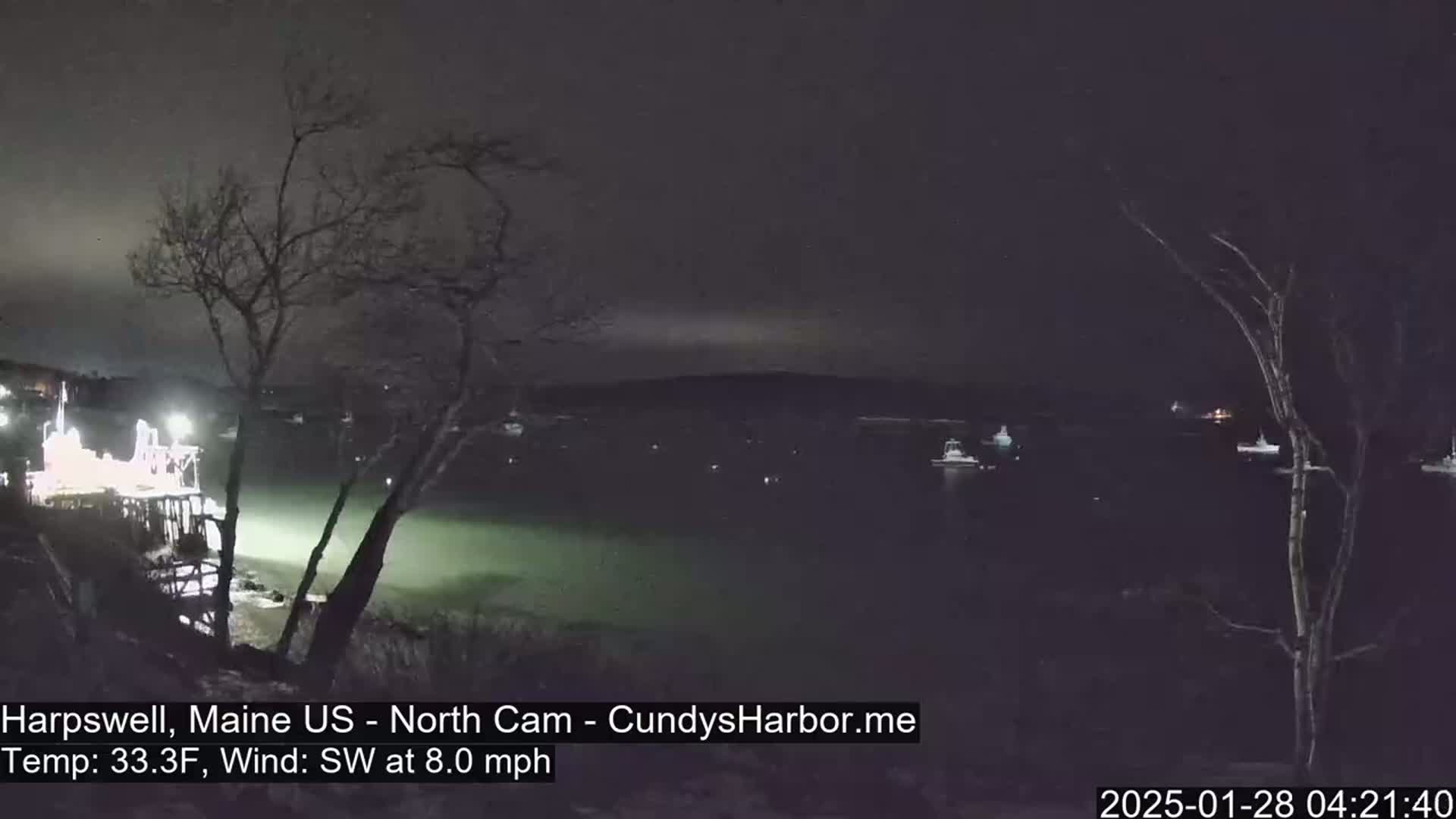 A nighttime view of a harbor with several boats at anchor under a dark sky, a southwest wind blowing at 8 mph, and a temperature of 33.3°F.