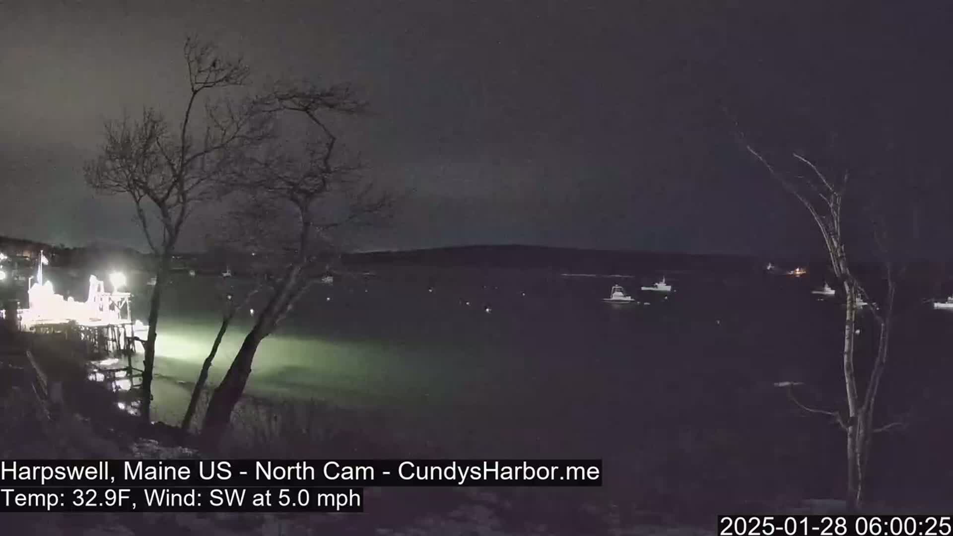 A nighttime view of a harbor with several boats at anchor under a dark sky, with a 5 mph southwest wind and a temperature of 32.9°F.