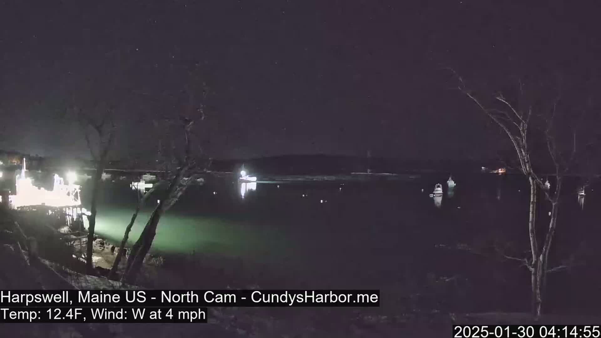 A nighttime view of a harbor with several boats, under a clear, starry sky and a 4 mph west wind, with the temperature at 12.4°F.