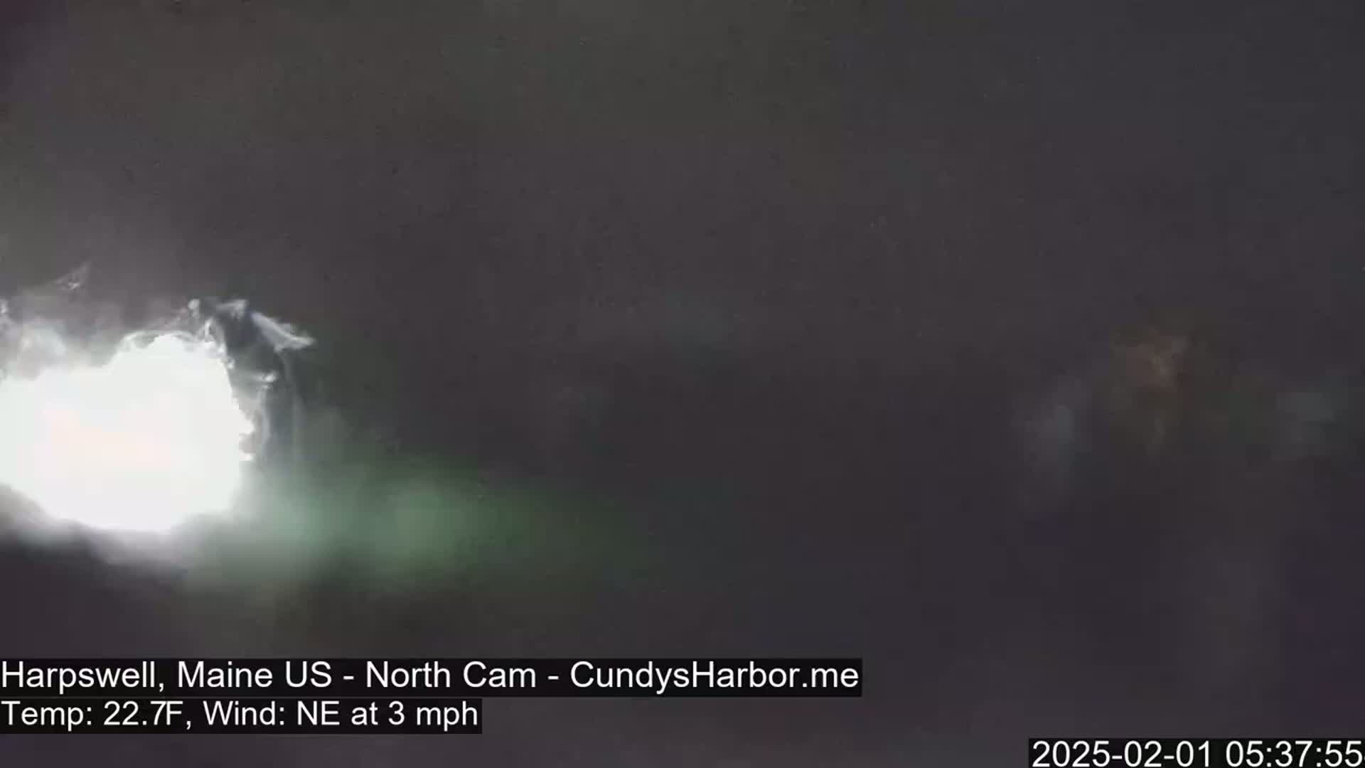A bright light shines from the left, illuminating a dark, possibly nighttime scene with a northeast wind at 3 mph.
