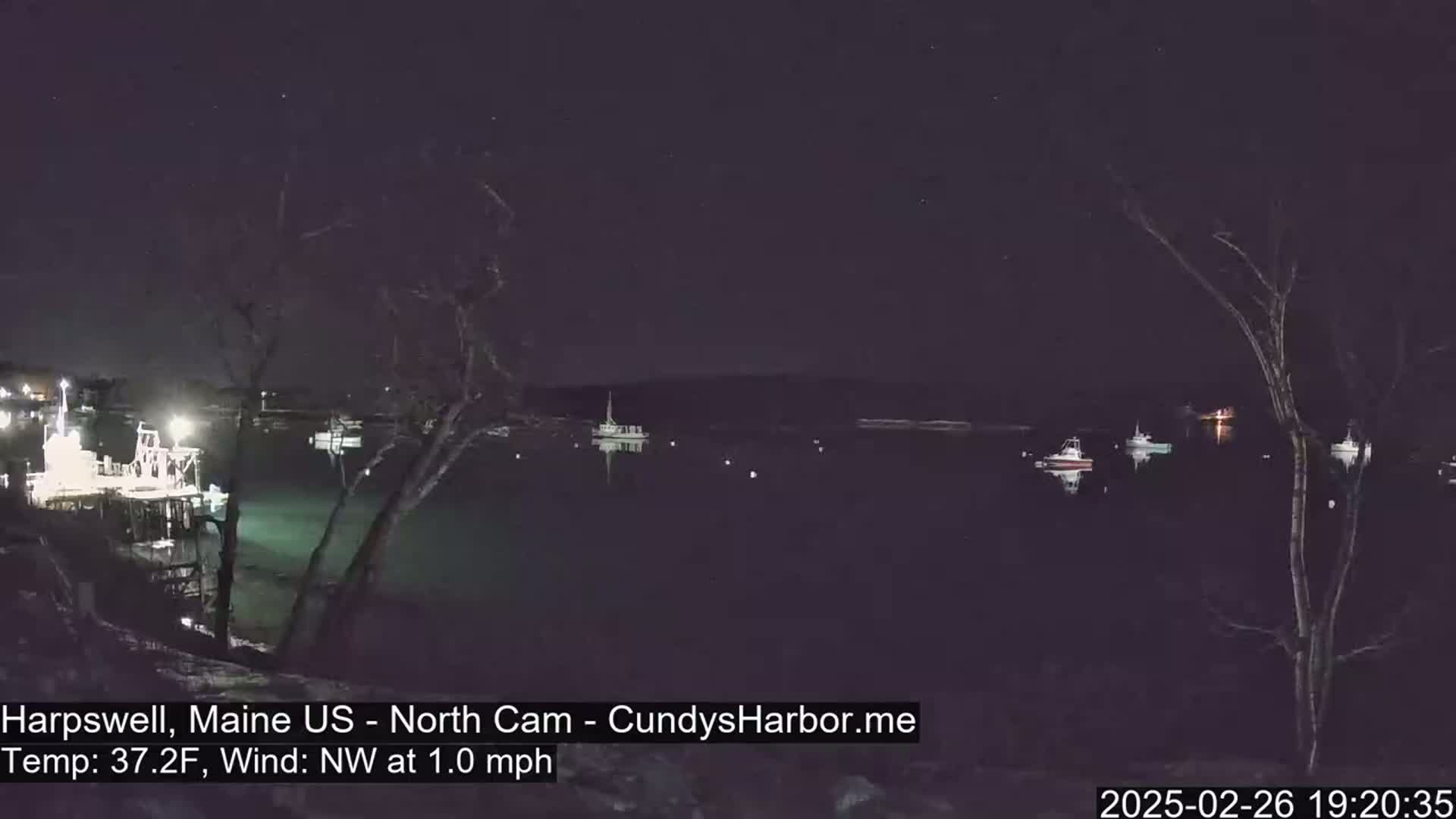 Several boats are moored in a dark harbor at night under a clear, starry sky with a light northwest wind.