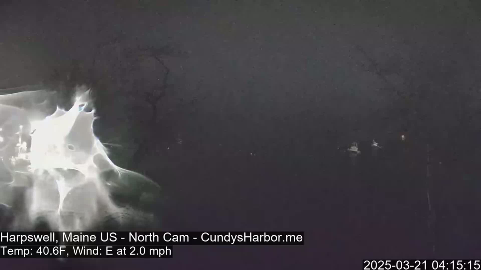 A dark, blurry image shows a body of water with a few indistinct objects on the surface, under overcast skies.
