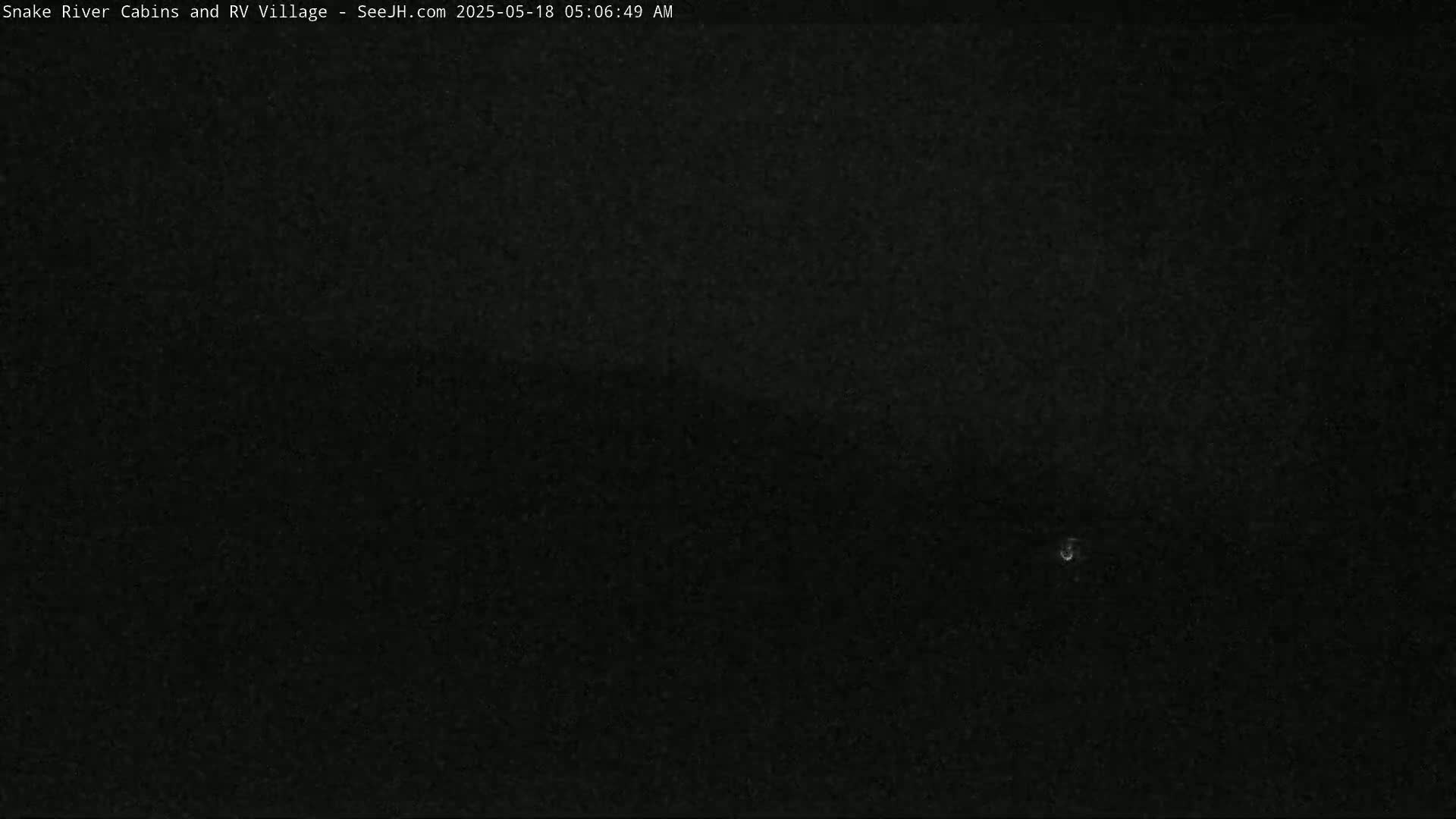 A nighttime, dark image shows a very faint, small, bright light in the center.