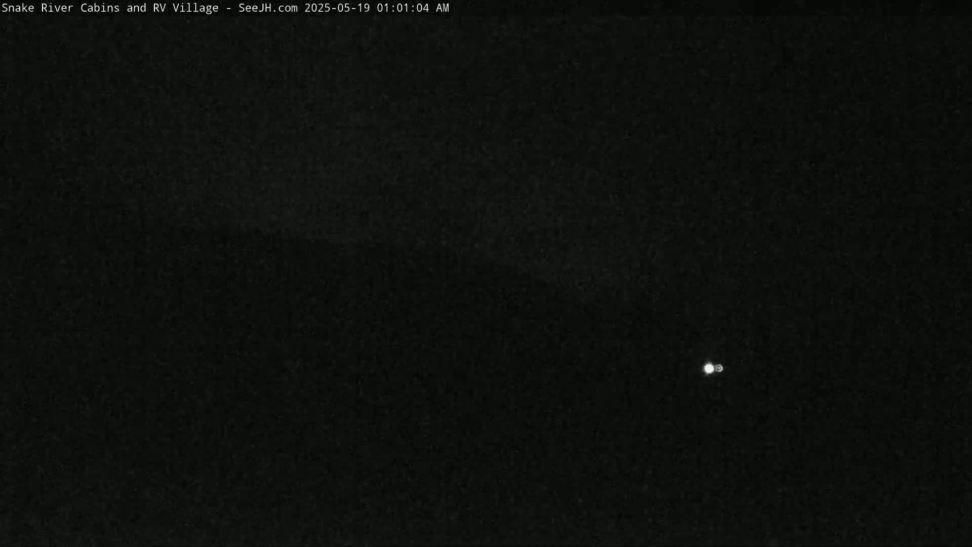 A very dark, nighttime scene shows a single, small, bright light in the center.