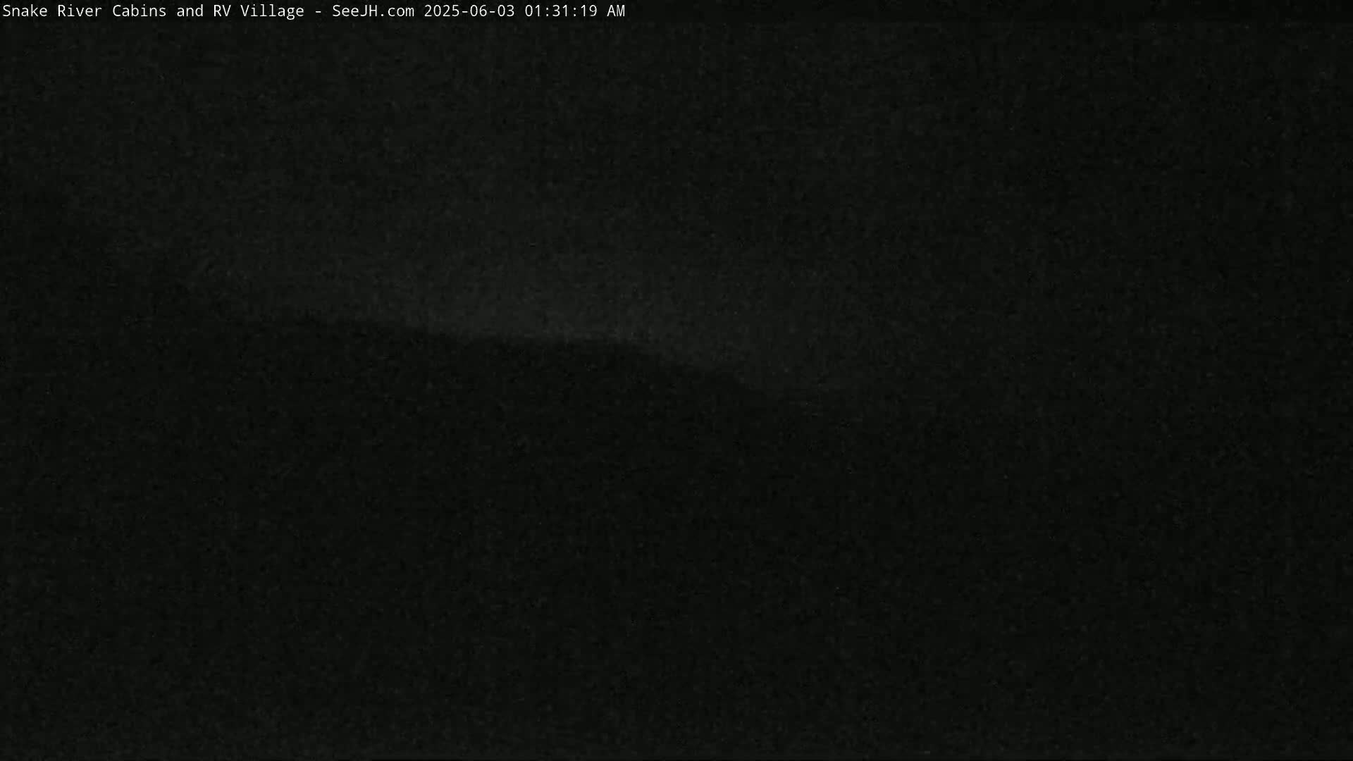 A dark, nighttime image shows a mostly featureless landscape under a clear, dark sky.