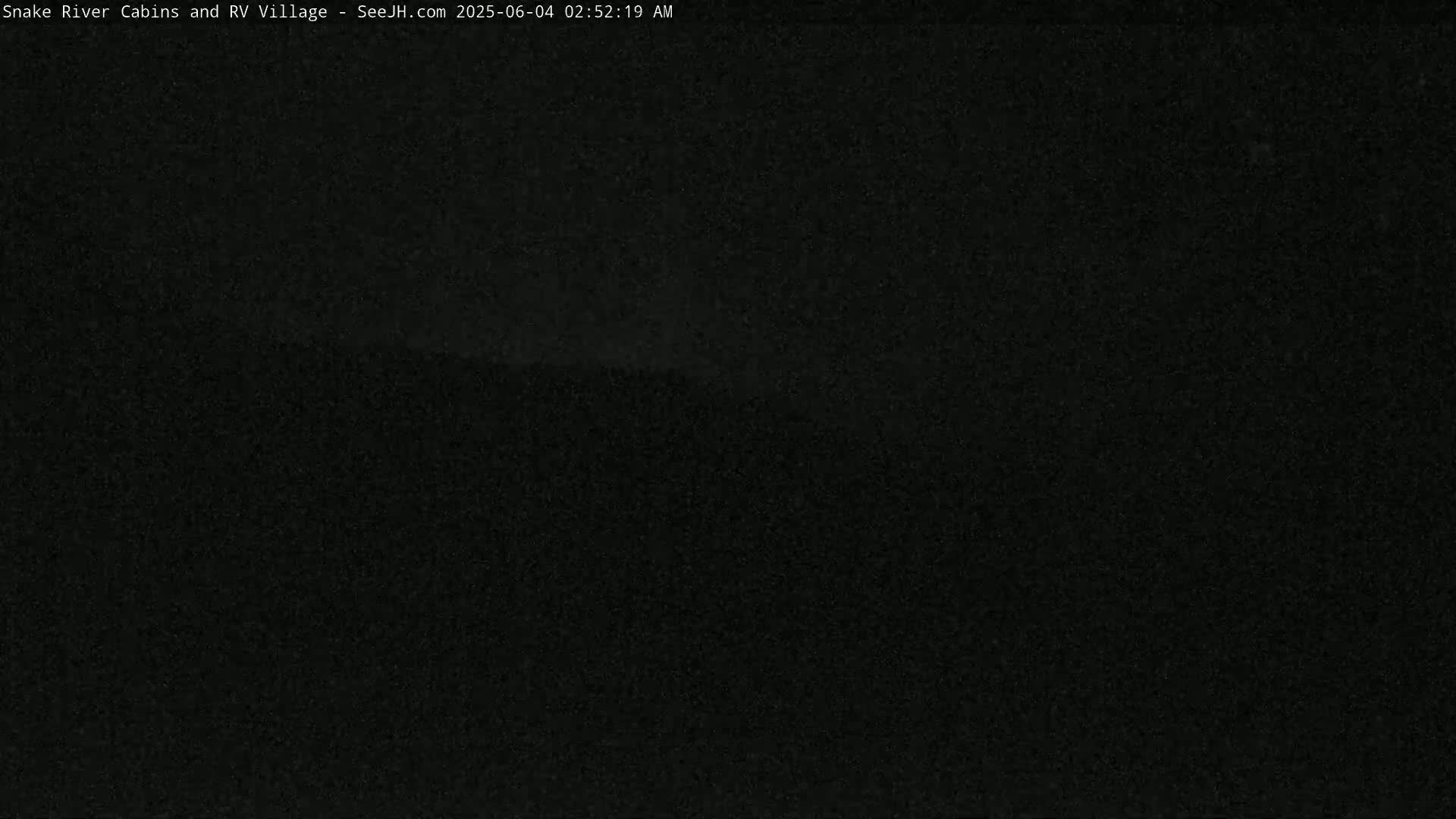 A dark, nighttime image shows a mostly black, grainy scene with a slightly lighter area in the center.