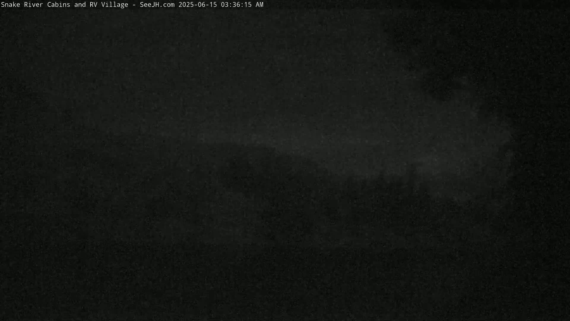 A dark, nighttime image shows a blurry, indistinct landscape under a mostly clear sky.