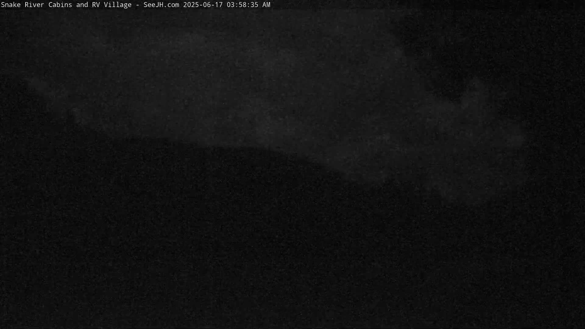 A dark, nighttime image shows a mostly obscured landscape under a cloudy sky.