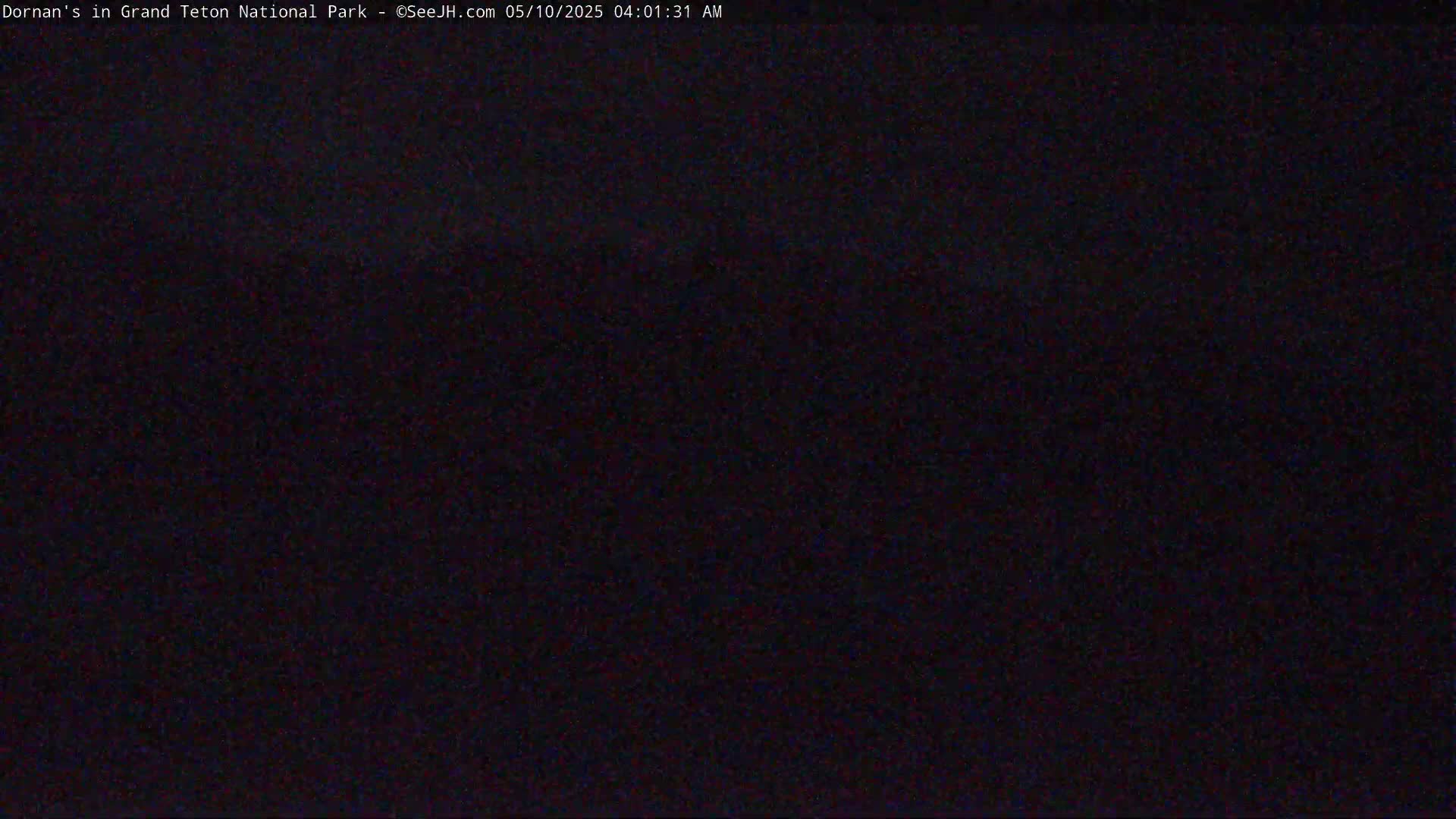 A very dark image shows a mostly black scene, likely nighttime outdoors.