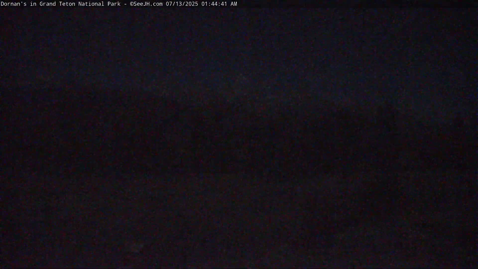A dark, nighttime outdoor scene shows a mostly obscured view of what appears to be a landscape.