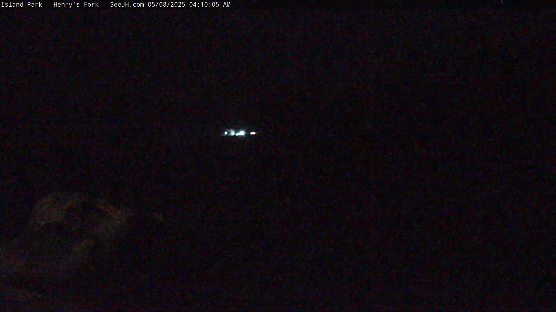 A nighttime, dark scene shows a distant, small line of lights in the sky.