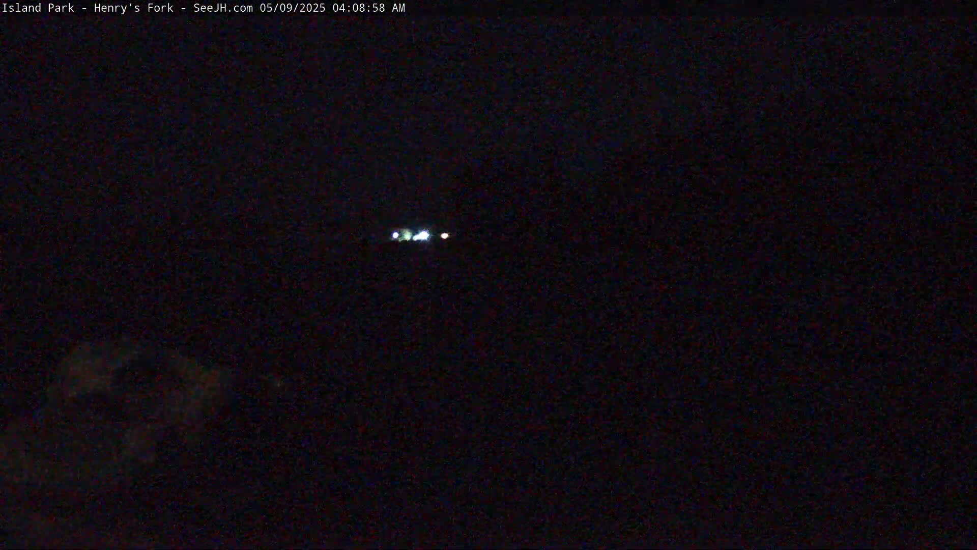 A dark, nighttime scene shows a few faint lights in the distance.