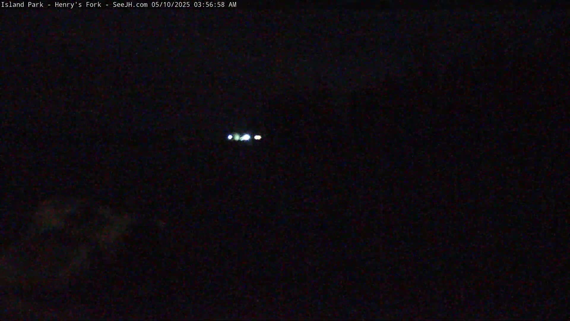A dark, nighttime scene shows a distant set of small, bright lights.