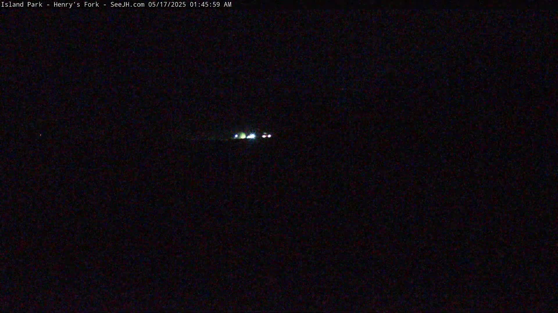 At night, a distant pair of vehicle headlights are visible in the darkness.