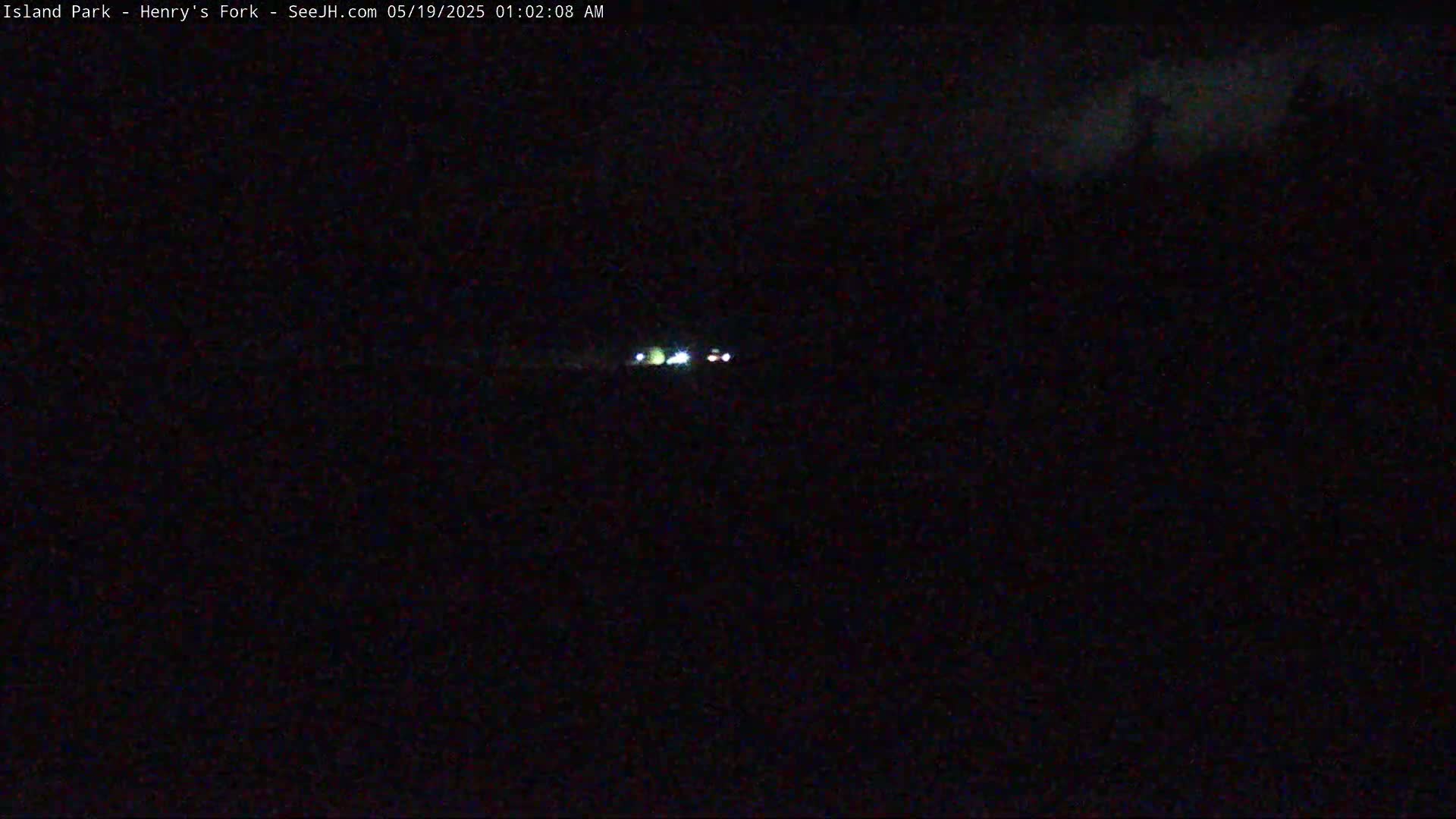 Headlights of vehicles are visible in the distance on a dark night.