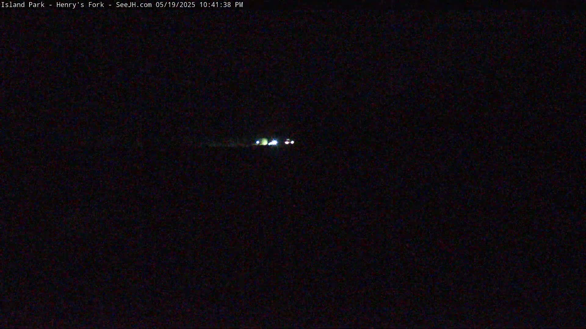 A nighttime, long-range view shows a few distant vehicle headlights on a dark road.