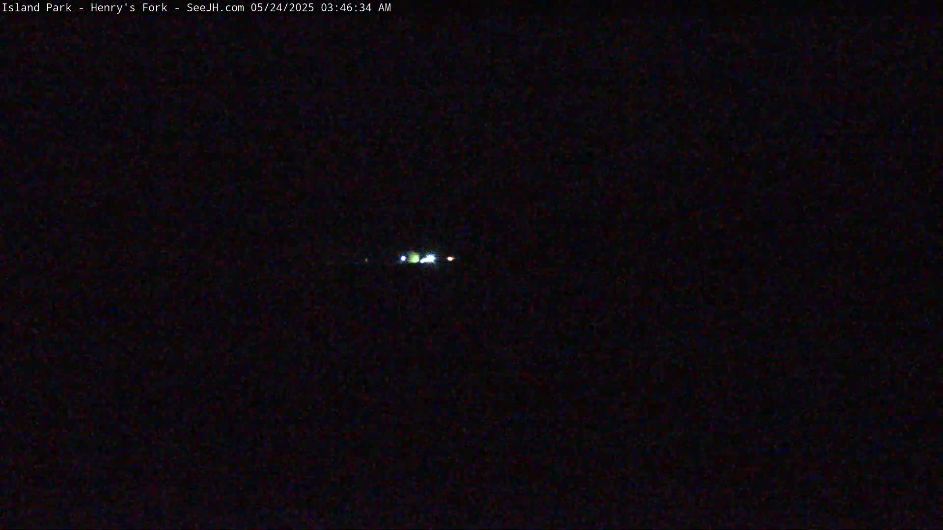 A nighttime, dark image shows a few faint lights in the distance.