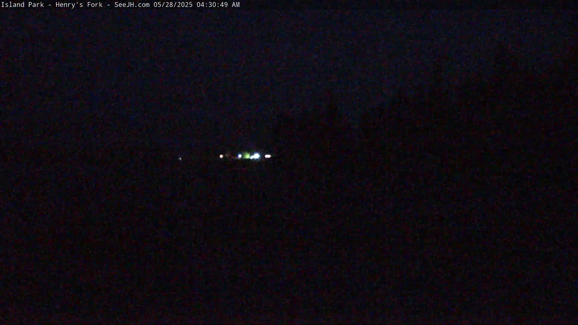 A nighttime, dark scene shows a few distant, faint lights in the middle of the frame.