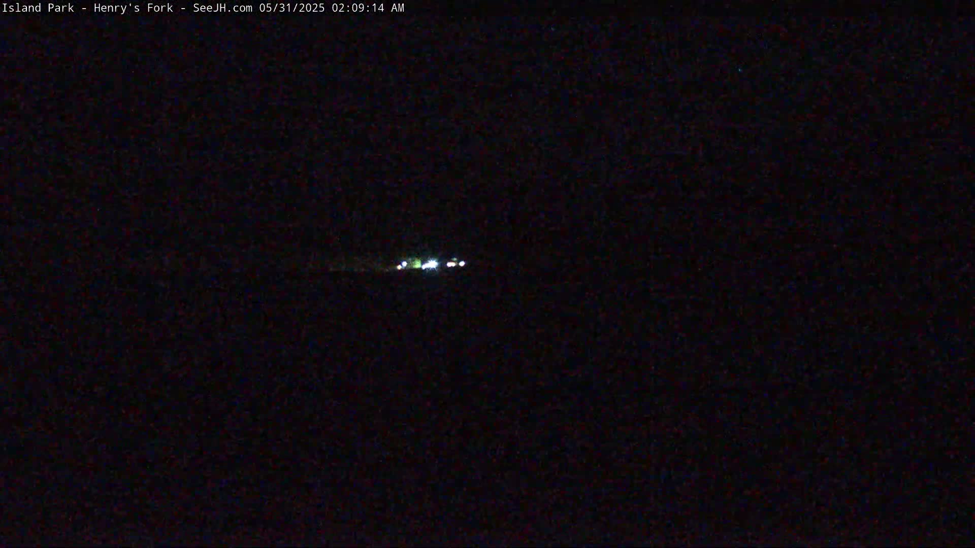 A nighttime long shot shows a few small lights in the distance under a dark sky.