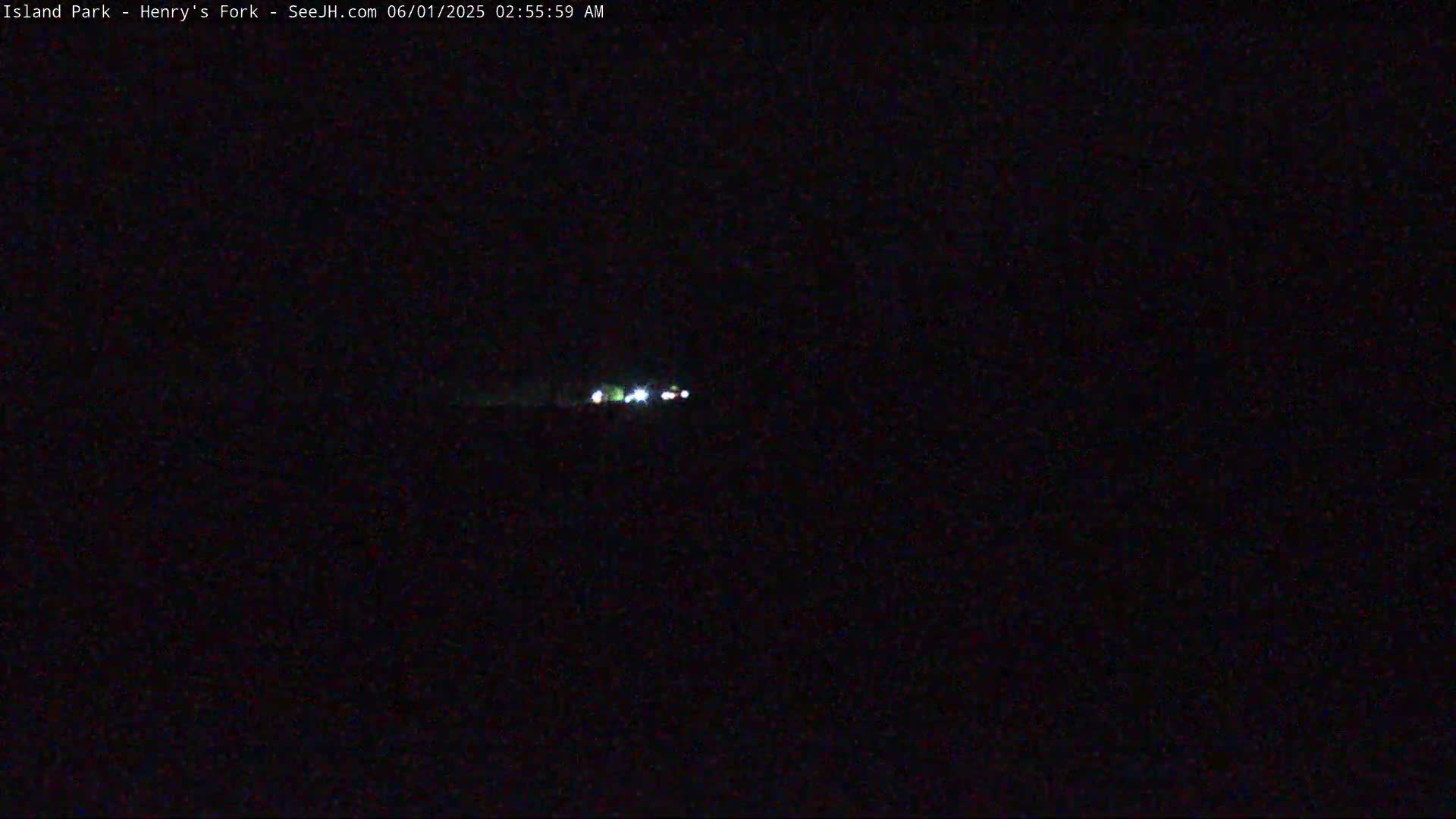 At night, a few faint lights are visible in the distance on a dark landscape.