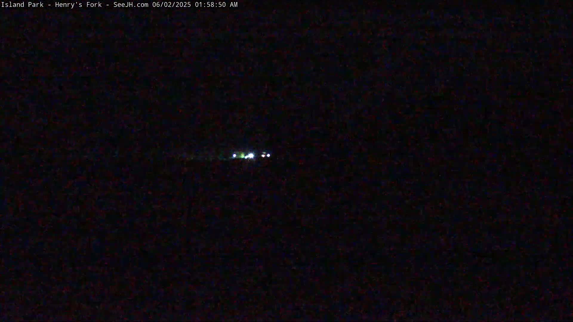 A dark, nighttime scene shows a few faint lights in the distance.